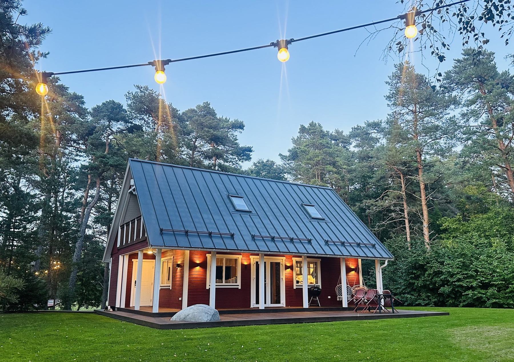 Rootsipunane peamaja rõdu ja terrassiga männimetsas