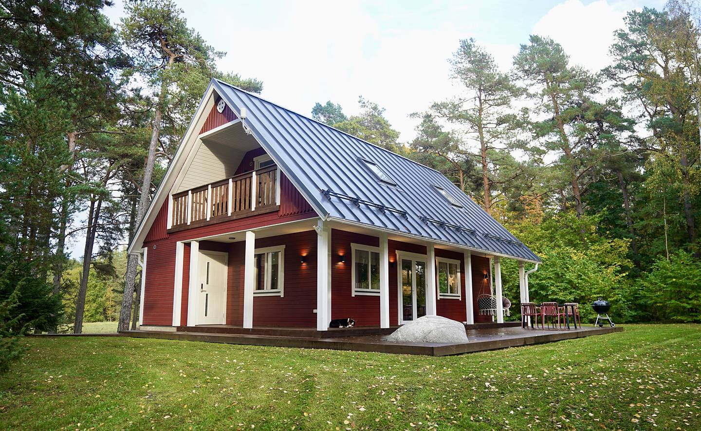 Rootsipunane peamaja rõdu ja terrassiga männimetsas